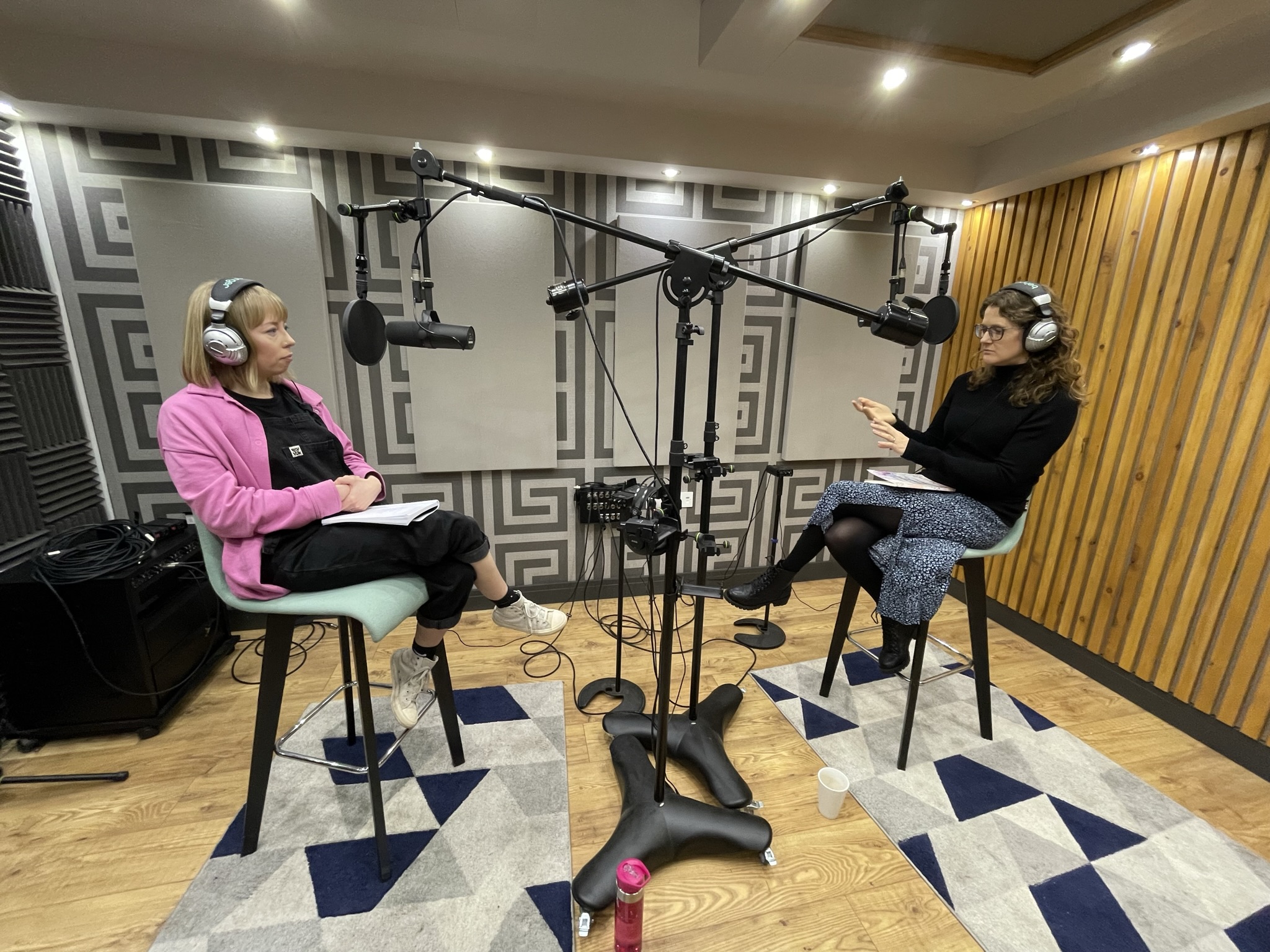 Two guests recording an audio podcast with suspended microphones and headphones at Podcast Studio Leicester